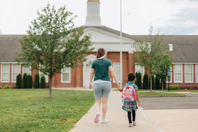 Young millennial mother sending daughter off back to school