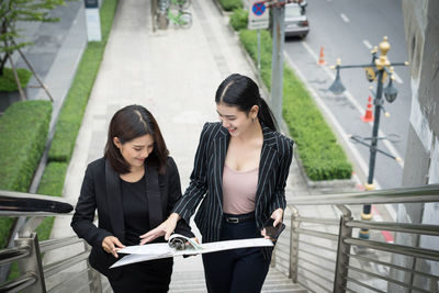 High angle view of smiling colleague discussing with folder on steps 