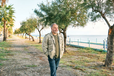 Happy middle-aged bearded man walking along promenade seaside. concept of leisure activities