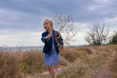 Blond long hair child girl in denim jacket walks on sea landscape. travelling hiking running outdoor