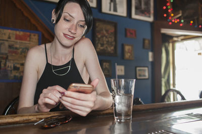 A young woman at a bar on her cell phone.