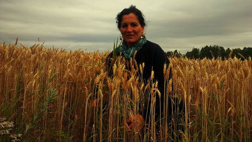 Portrait of smiling young woman standing on field against sky