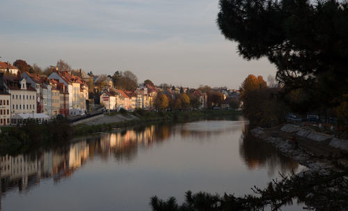 Lake by houses in town against sky