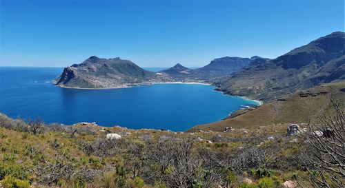 Panoramic view of sea and mountains against clear blue sky
