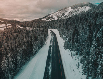 Snow covered road by mountain against sky