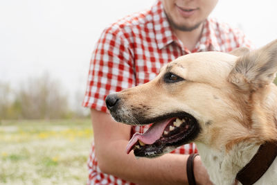 Summer leisure time, pet care and training. happy man plays with mixed breed shepherd dog