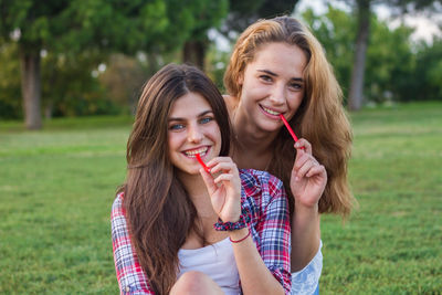 Portrait of young women eating candies on field