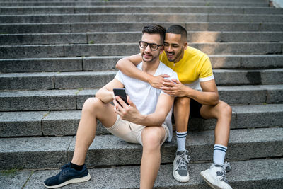 Full length portrait of young couple sitting outdoors