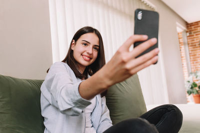 Portrait of smiling young woman using mobile phone