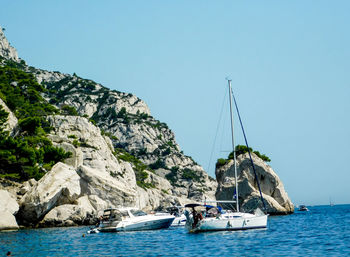 Sailboats sailing on sea against clear blue sky