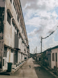 Empty road amidst buildings in city against sky