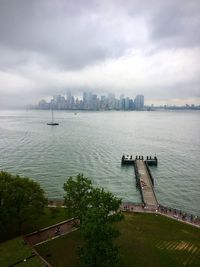 Scenic view of sea by city buildings against sky