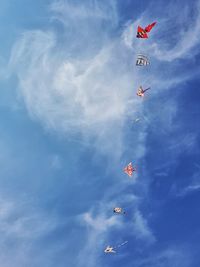 Low angle view of kites flying against blue sky