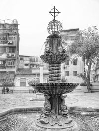 Fountain in park against buildings in city