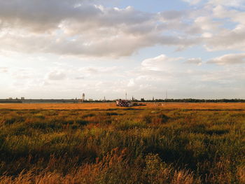 Scenic view of field against cloudy sky