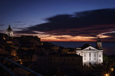 Houses in town against cloudy sky during sunset