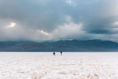 People on beach against sky during winter