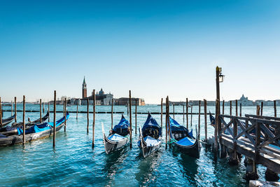 High angle view of gondolas moored in canal against clear blue sky