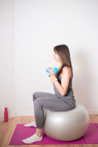 Young woman sitting on wall at home