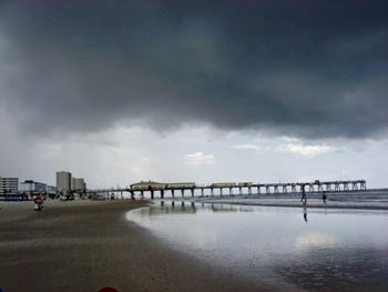 Pier on sea against cloudy sky