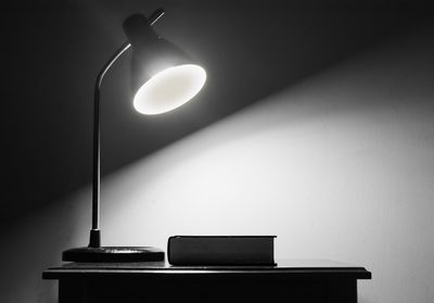 Close-up of illuminated lamp by book on table