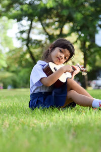Cute girl playing guitar on lawn