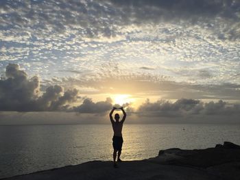 Silhouette man standing on beach against sky during sunset