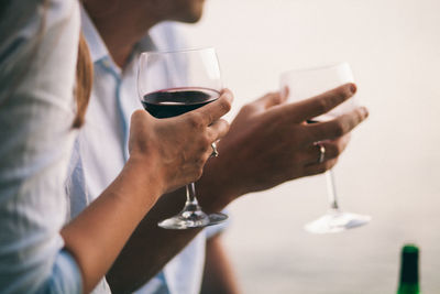 Midsection of couple holding wineglasses