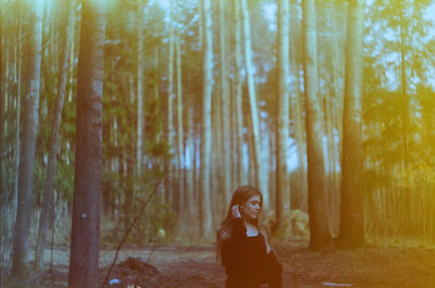 Portrait of woman standing by trees in forest