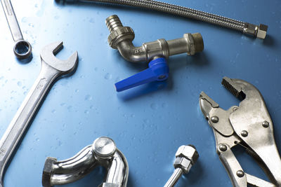 High angle view of tap amidst metallic hand tools on table