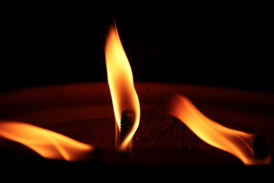 Close-up of burning candle against black background