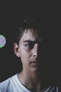 Close-up portrait of a young man against black background