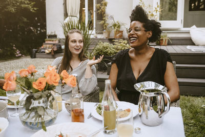 Female talking to young friend at table during social gathering