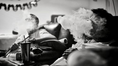 Friends smoking hookah while relaxing on sofa at home