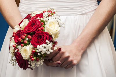 Midsection of couple holding bouquet