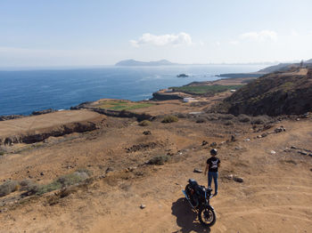 People riding motorcycle on sea shore against sky