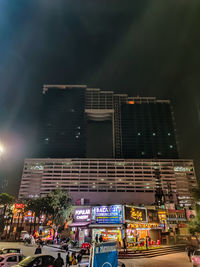 People on illuminated street against buildings in city at night