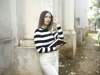 Young woman standing against wall