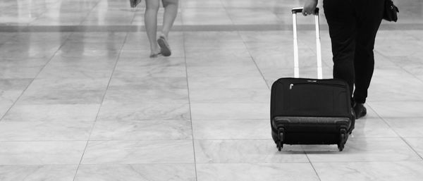 Low section of woman with suitcase walking at airport