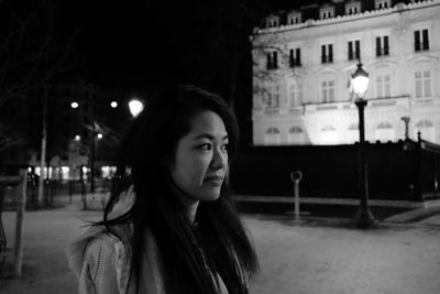 Portrait of beautiful young woman standing in city at night