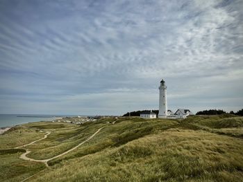 Lighthouse by sea against sky