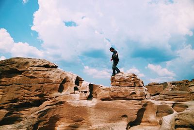 Low angle view of man standing on rock against sky
