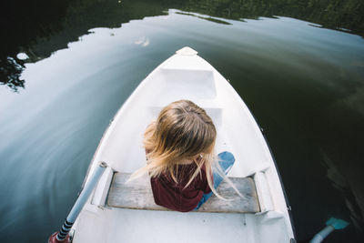 Rear view of girl sitting on boat sailing in lake
