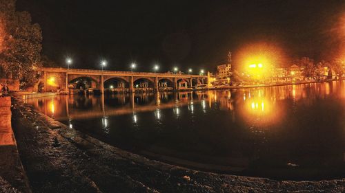 Illuminated bridge over river at night