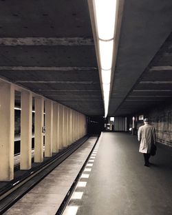 Rear view of woman walking on illuminated corridor