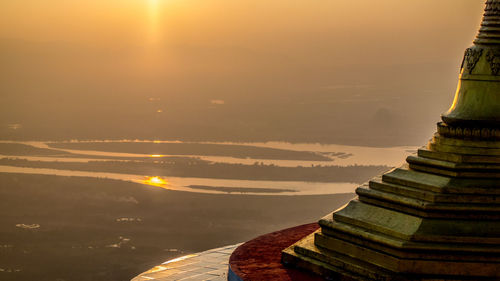 Close-up of stupa against rivers at sunset