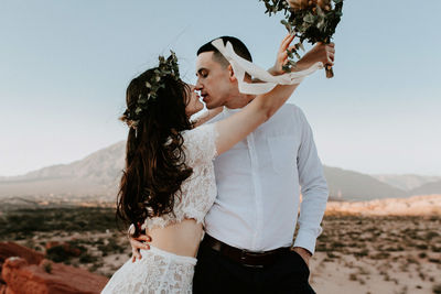 Midsection of couple holding hands against sky