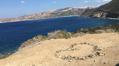 Heart shape on shore by sea against sky