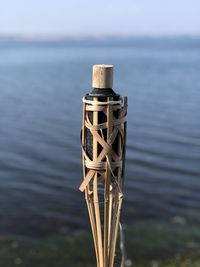 Close-up of wooden post in lake against sky