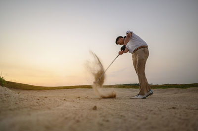 Full length of man playing golf on sand